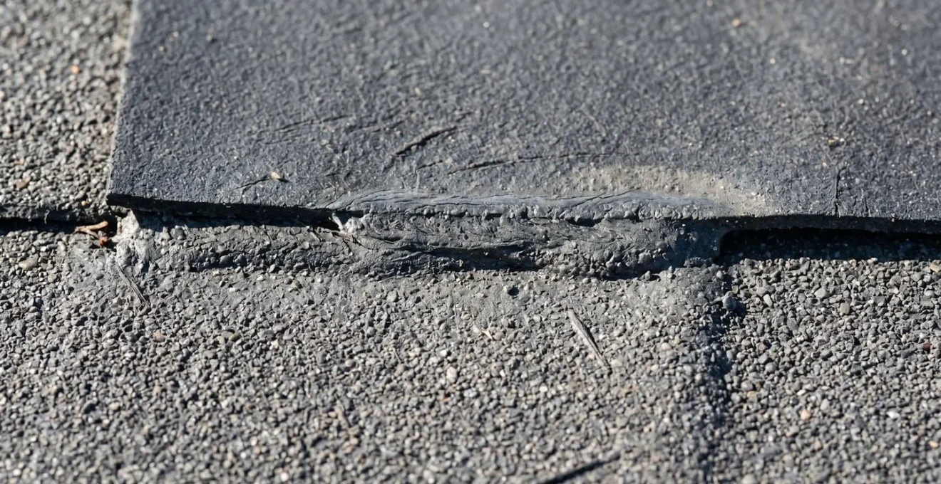 Gros plan macro sur le chevauchement de deux couches de membrane élastomère montrant la soudure au chalumeau et la texture granulée du revêtement